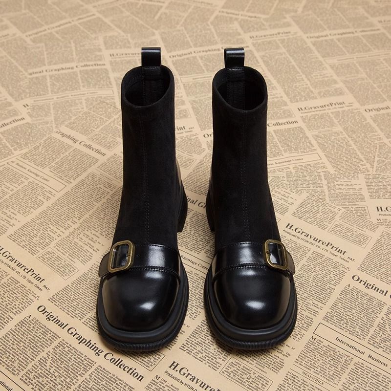 Paire de bottines noires vue de face, tiges en daim souple, bouts carrés en cuir brillant ornés d'une boucle dorée. 5