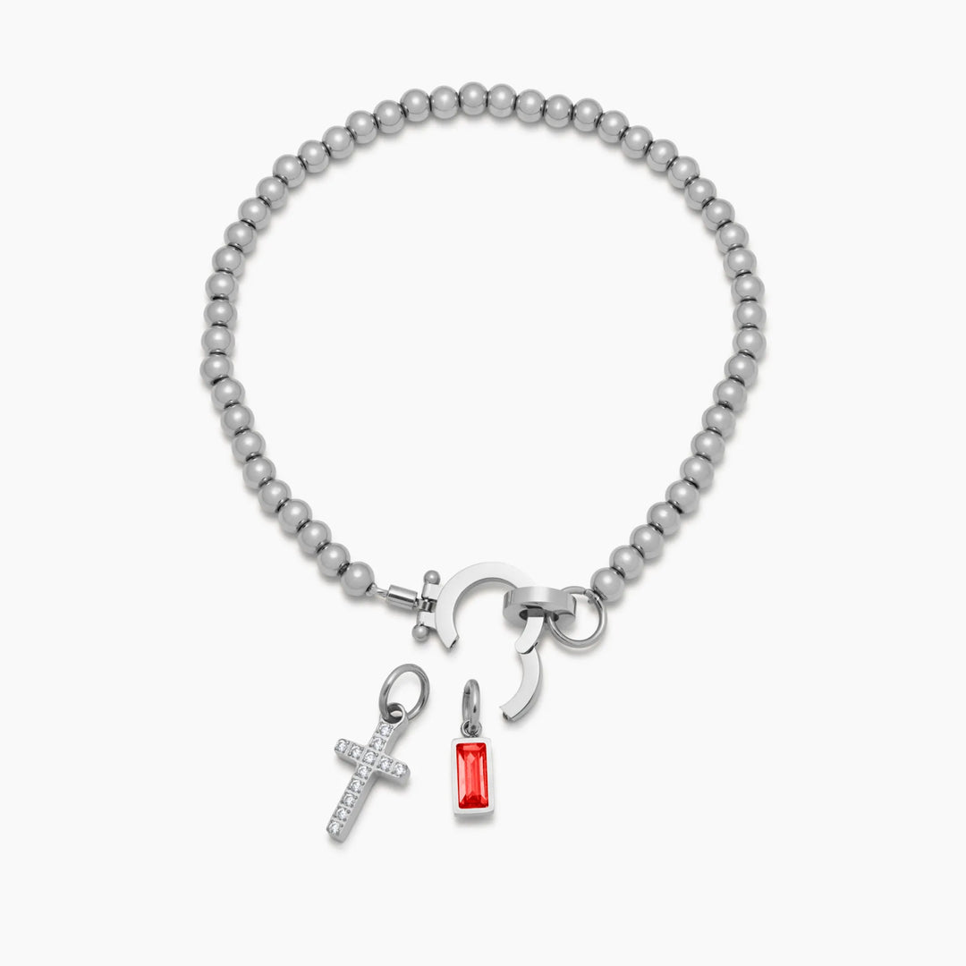 Bracelet argenté à perles, fermoir ouvert, avec la croix de strass et la pierre rouge présentées séparément en dessous. 10