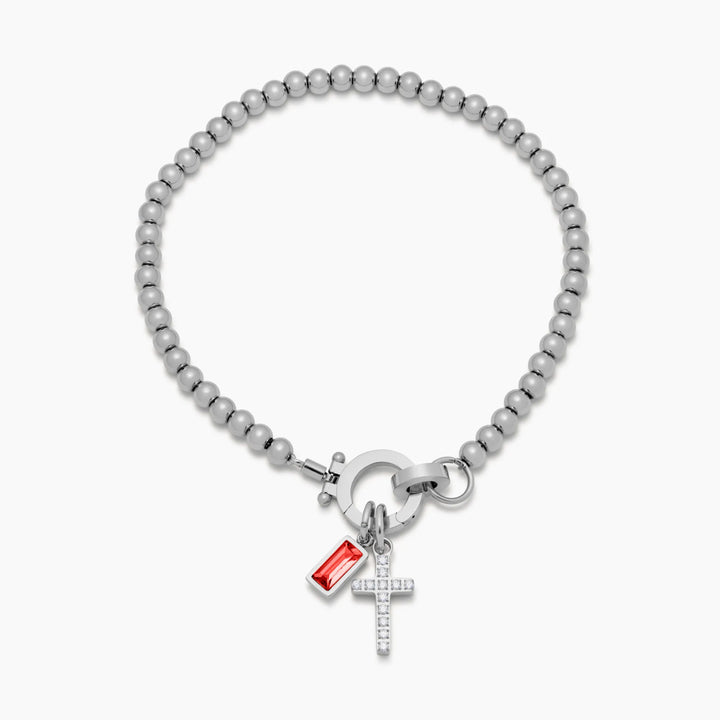 Bracelet argenté à perles posé à plat, avec croix sertie de strass et pierre rouge rectangulaire accrochées au fermoir. 9