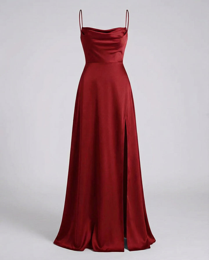 Robe longue satinée rouge bordeaux vue de face à plat sur fond gris, fines bretelles, col bénitier et fente latérale. 2