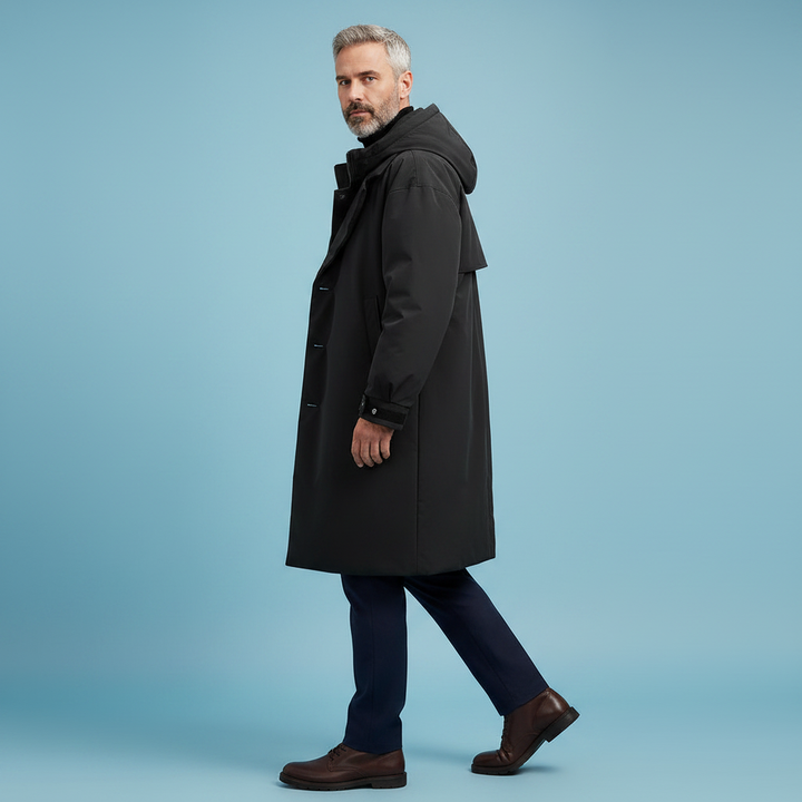 Homme aux cheveux gris vu de profil en manteau noir à capuche, avec pantalon bleu marine et chaussures marron. 6