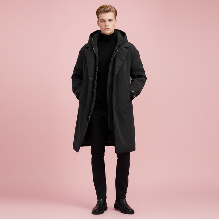 Homme debout de face portant le manteau noir ouvert, mains dans les poches, avec pantalon noir et bottines. 3