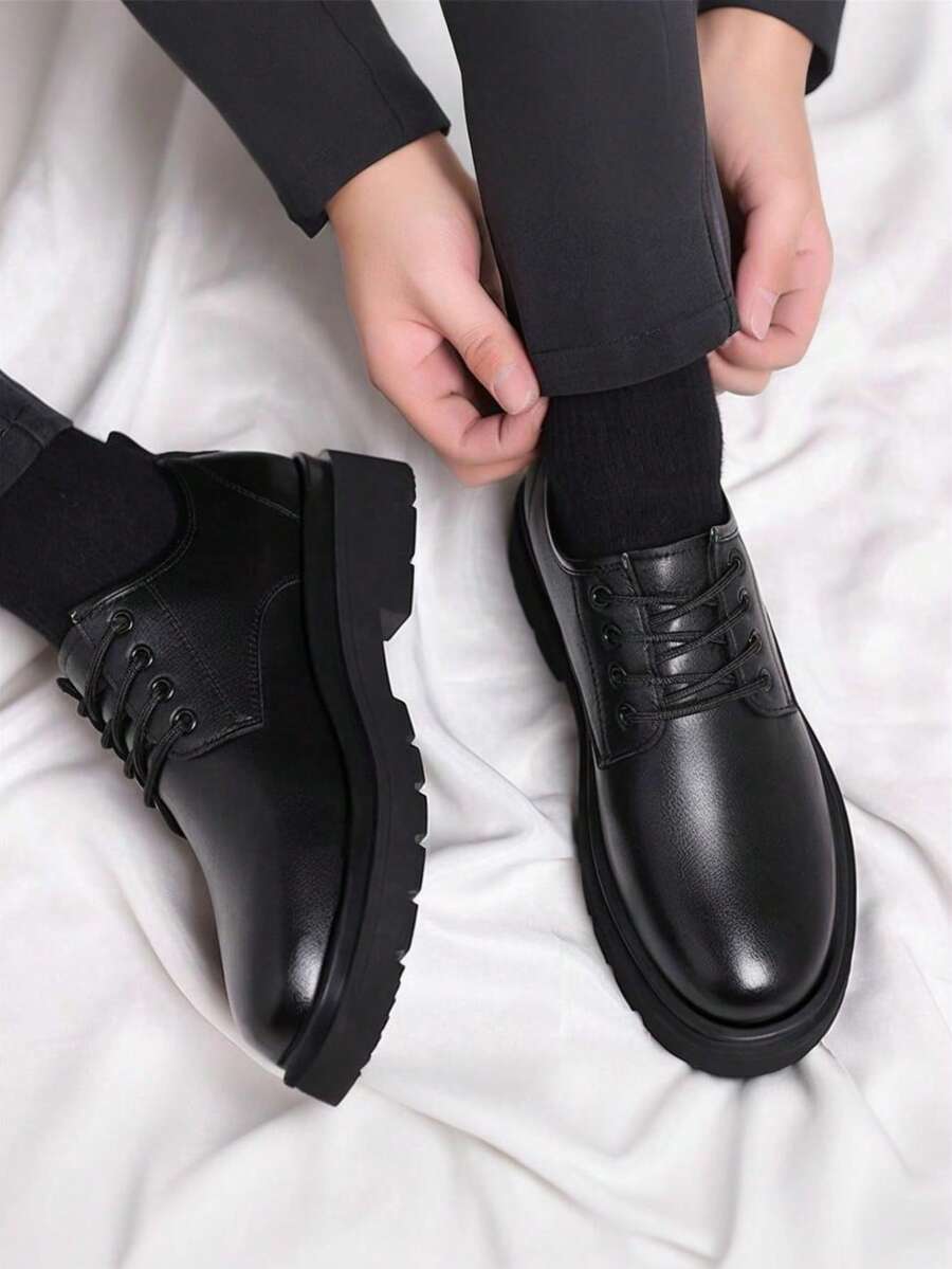 Homme assis ajustant son pantalon, derbies noires lacées aux pieds, vue de dessus sur drap blanc 3