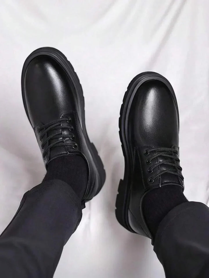 Vue plongeante sur les bouts arrondis brillants des derbies noires portées avec un pantalon sombre 4