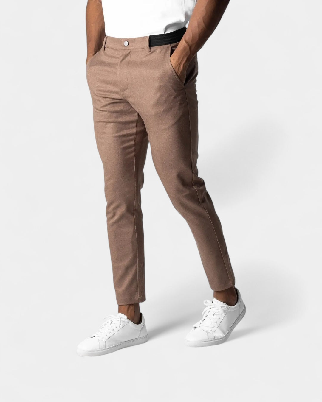 Pantalon couleur taupe porté par un homme, mains dans les poches, avec baskets blanches et haut blanc 5