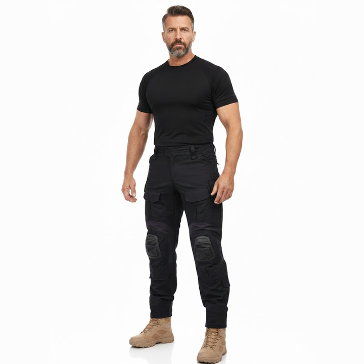 Homme en pied de face, vêtu du pantalon noir, d'un t-shirt noir et de bottines beiges, sur fond blanc. 7