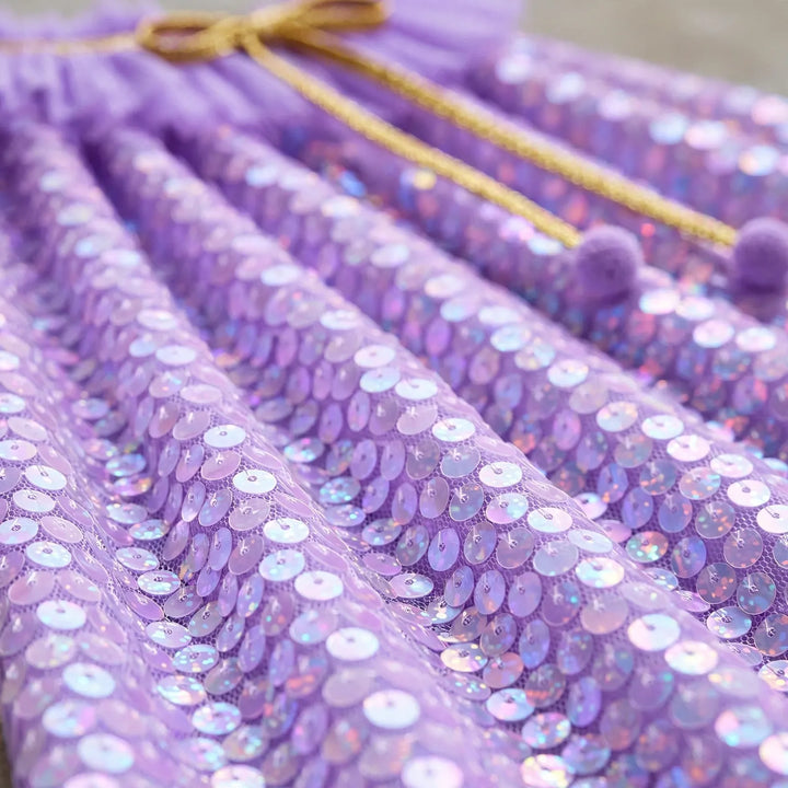 Gros plan sur la cape à sequins violets irisés, avec cordon doré et pompons 3