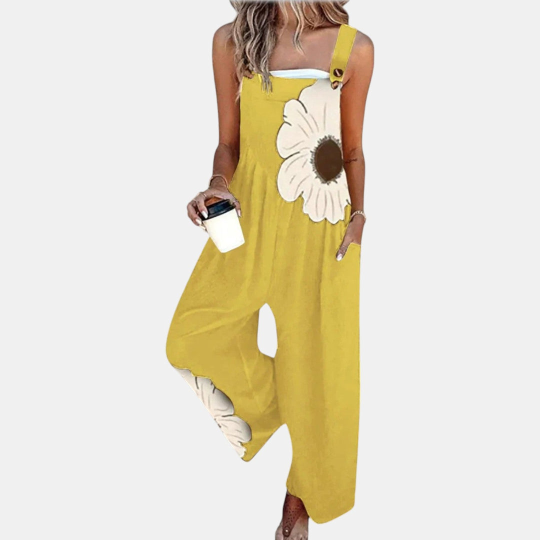 Salopette jaune portée de face avec une grande fleur crème sur le buste, gobelet à la main 9