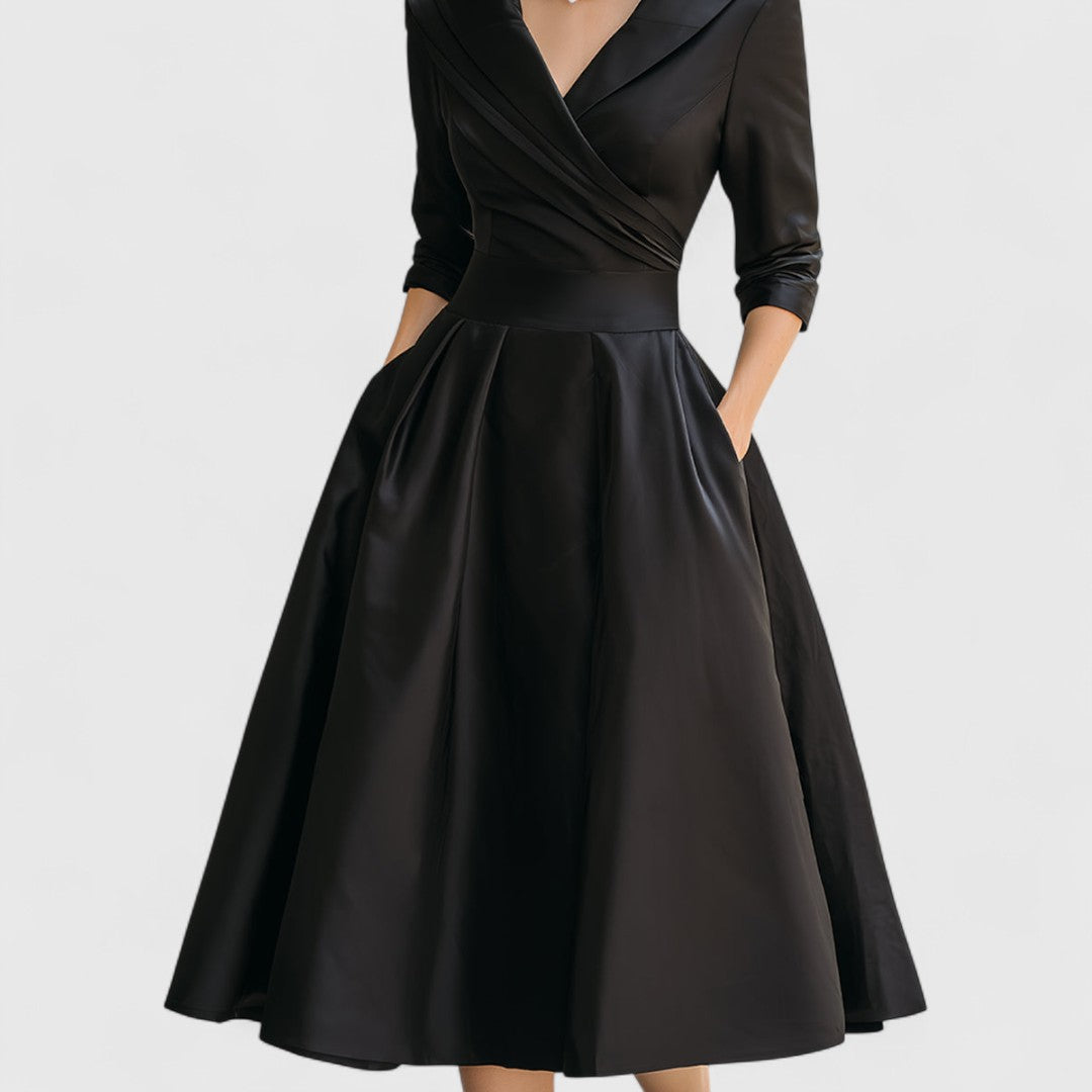 Robe noire cadrée de la taille aux pieds, montrant la jupe ample à plis, la ceinture et les poches. 11