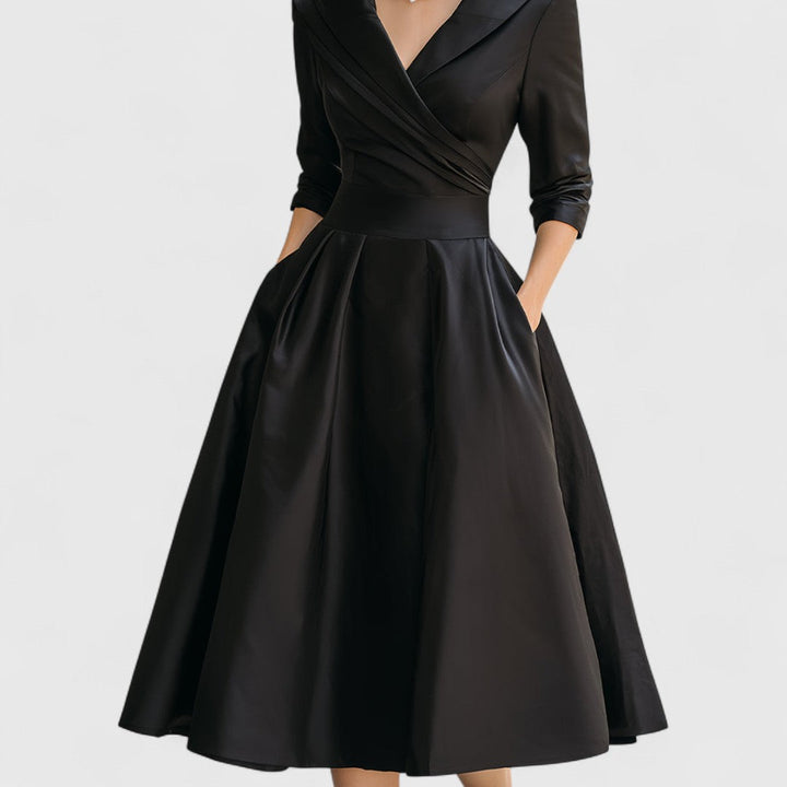 Robe noire cadrée de la taille aux pieds, montrant la jupe ample à plis, la ceinture et les poches. 11