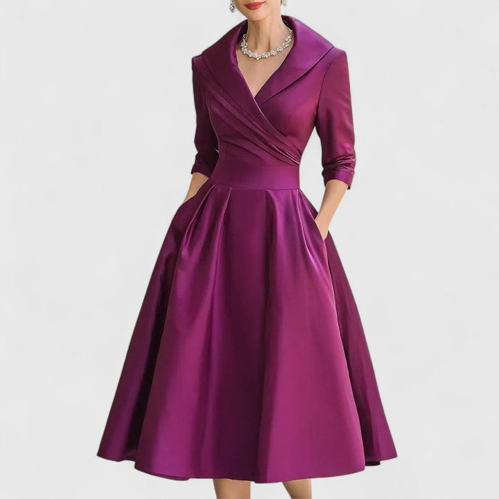 Même robe en violet prune portée de face, col châle, taille marquée et jupe évasée mi-longue. 5
