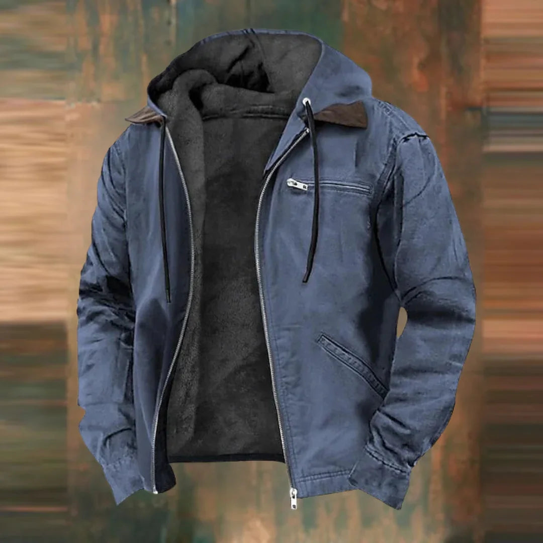 Même veste à capuche en version bleu ardoise, zip ouvert sur la doublure polaire, présentée sur fond flou aux tons bruns. 2