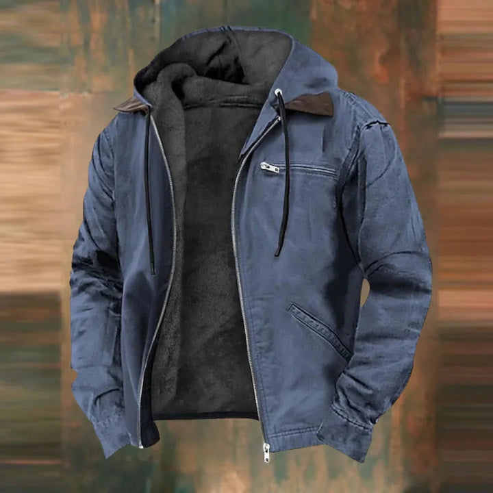 Même veste à capuche en version bleu ardoise, zip ouvert sur la doublure polaire, présentée sur fond flou aux tons bruns. 2