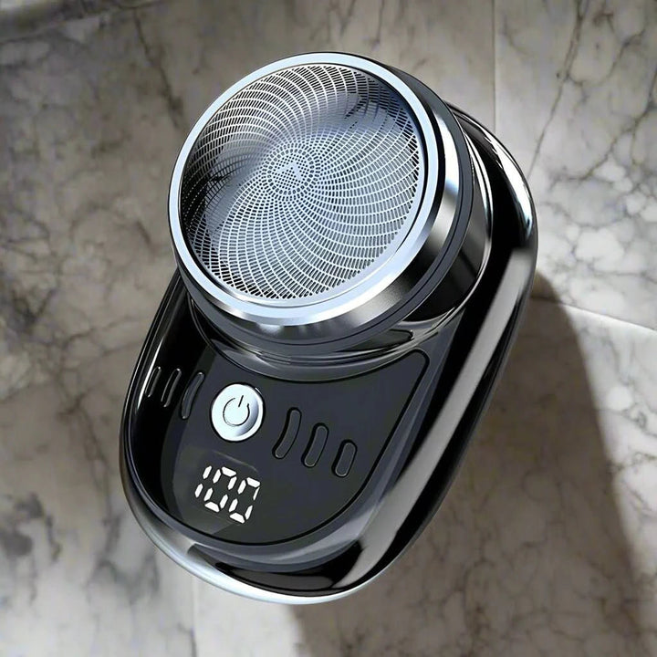 Rasoir noir vu de dessus, posé sur un fond de marbre gris, avec sa grille ronde et son écran numérique. 5