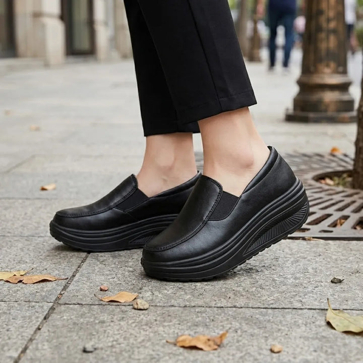 Pieds de femme portant les mocassins noirs à semelle compensée, sur un trottoir en ville 2