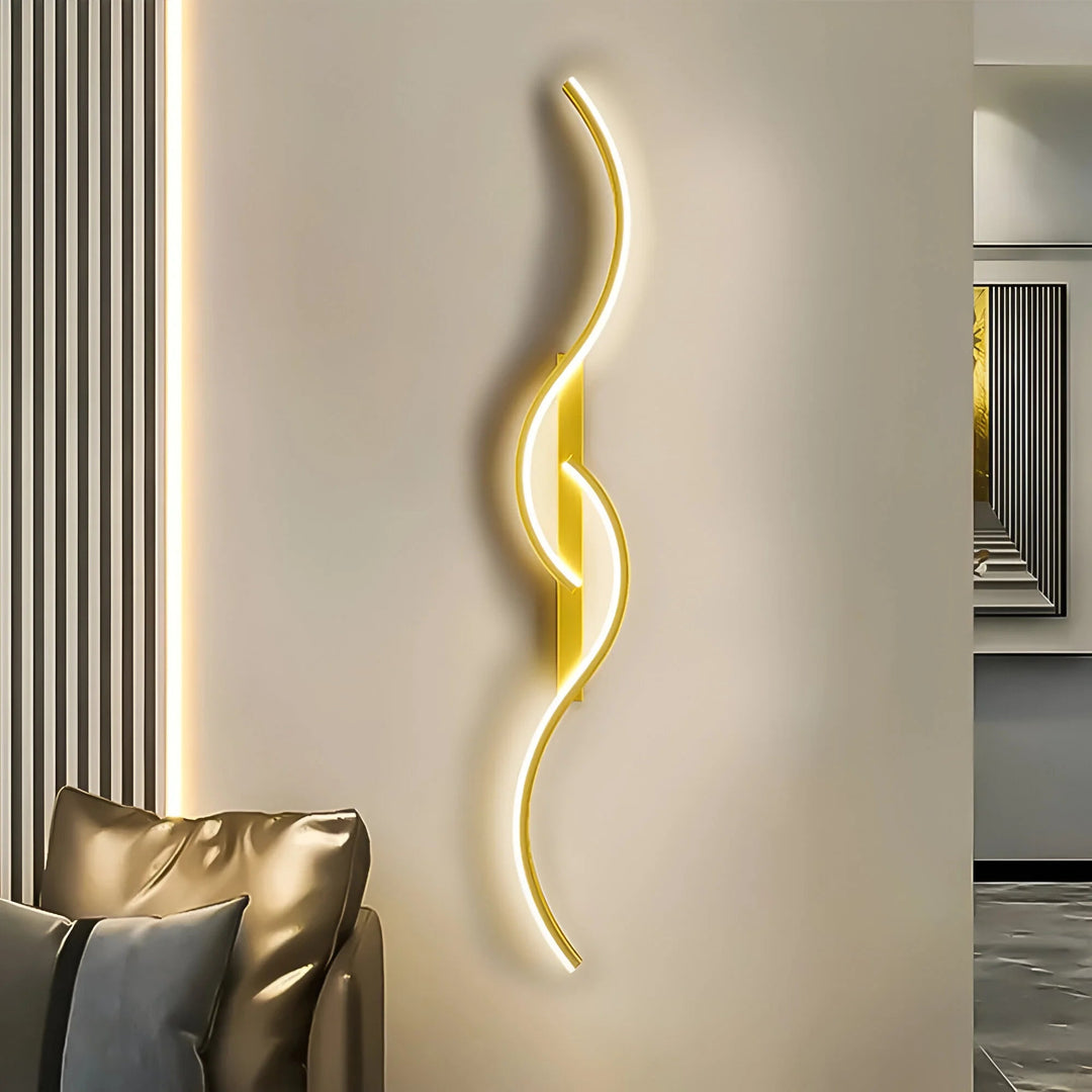Applique murale LED dorée en courbes entrelacées, allumée près d'un canapé en cuir dans un salon 1