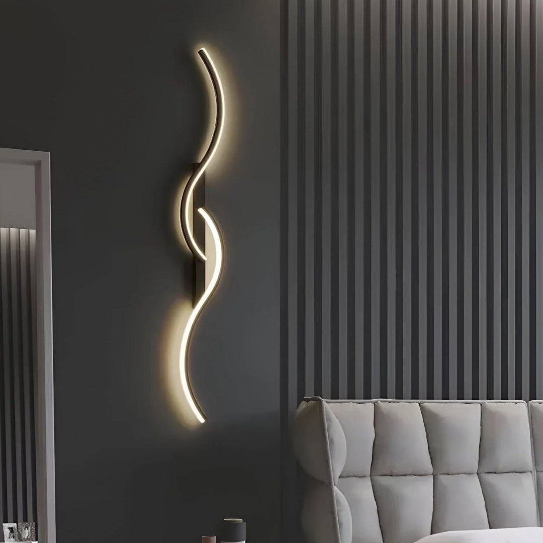 Applique noire aux courbes lumineuses sur un mur gris foncé, au-dessus d'un canapé capitonné gris clair 6