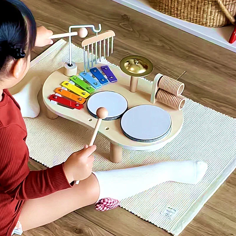 Vue de dessus d'une enfant assise sur un tapis qui frappe un tambour avec une baguette 2