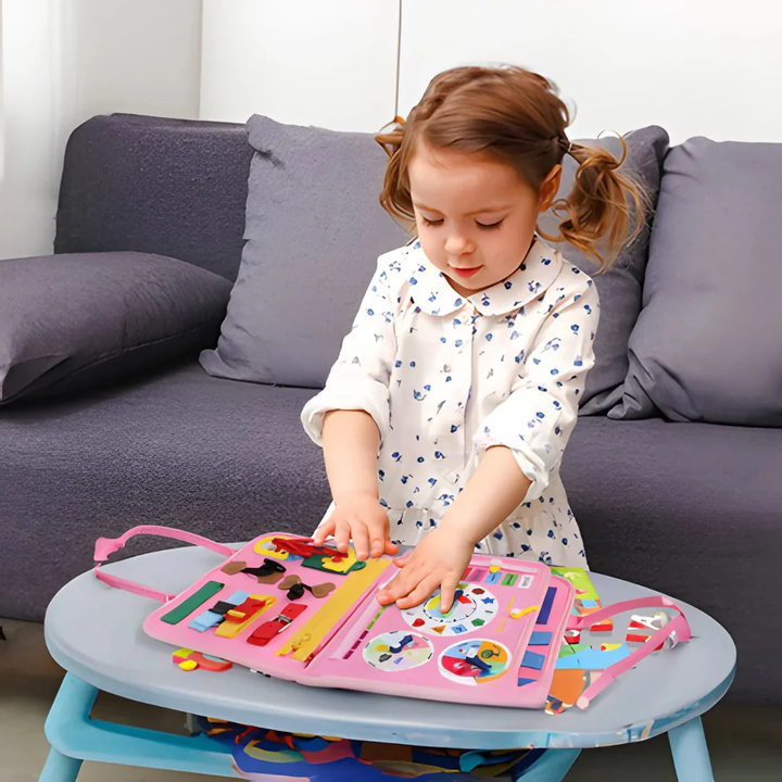 Fillette en robe fleurie debout devant une table basse, touchant les pages du livre rose ouvert 5