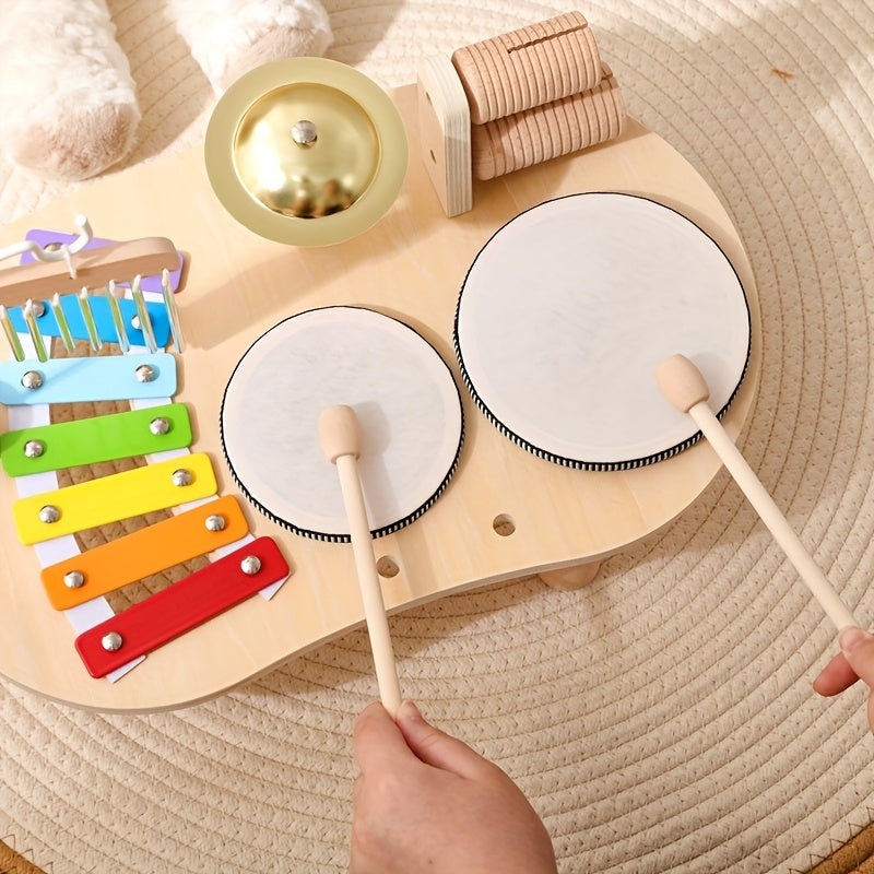 Vue de dessus d'une main d'enfant frappant les deux tambours blancs avec des baguettes en bois, à côté du xylophone coloré. 5