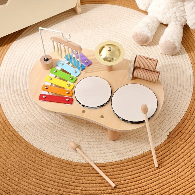 Table musicale vue de dessus sur un tapis rond, avec deux baguettes en bois posées devant, xylophone, cymbale et tambours. 8