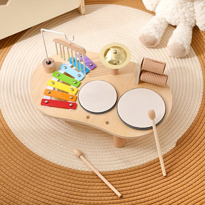 Table musicale vue de dessus sur un tapis rond, avec deux baguettes en bois posées devant, xylophone, cymbale et tambours. 8