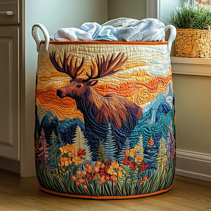 Panier matelassé orné d'un élan brodé devant un ciel orangé, des montagnes et des fleurs, rempli de serviettes bleues. 6