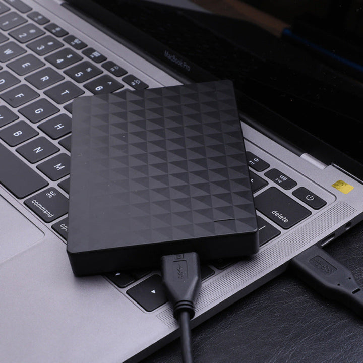 Disque noir à motif en relief posé sur le clavier d'un ordinateur portable, câble USB 3.0 branché 2