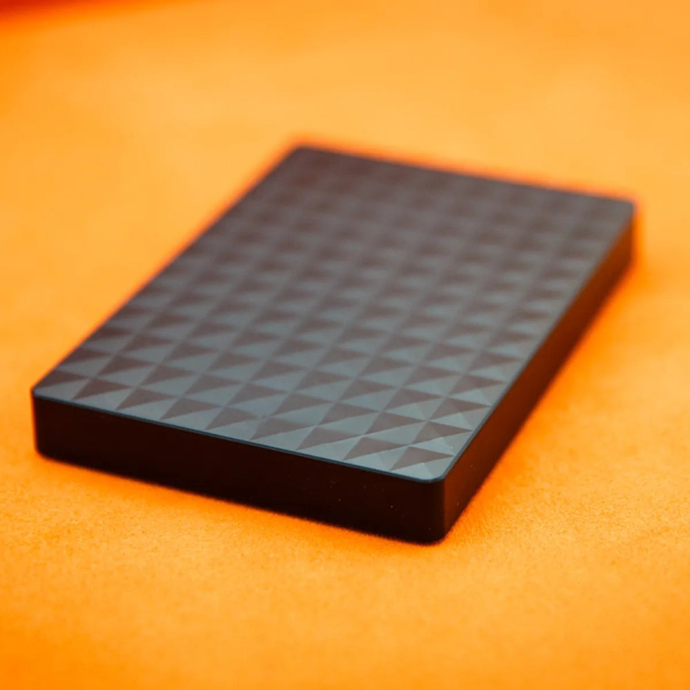 Gros plan en perspective sur la surface texturée du boîtier noir, posé sur un fond orange 4