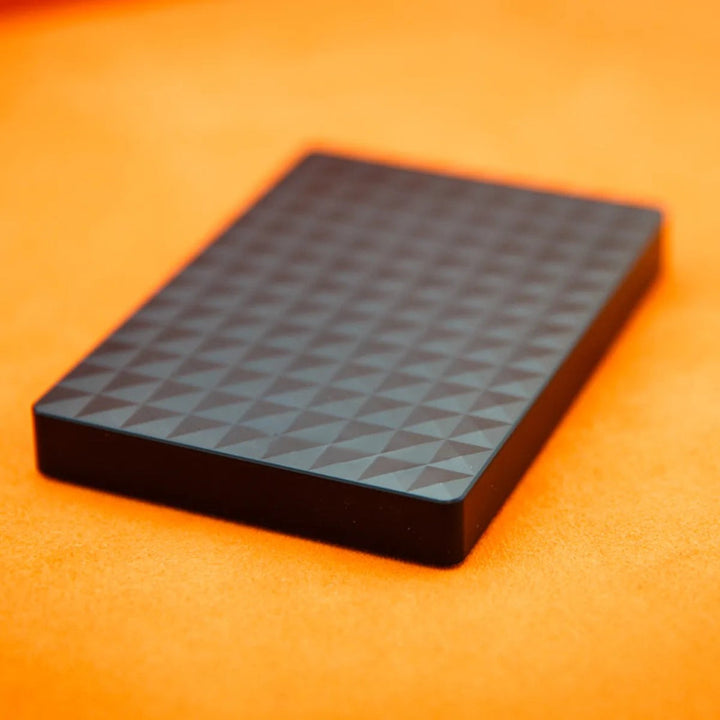 Gros plan en perspective sur la surface texturée du boîtier noir, posé sur un fond orange 4