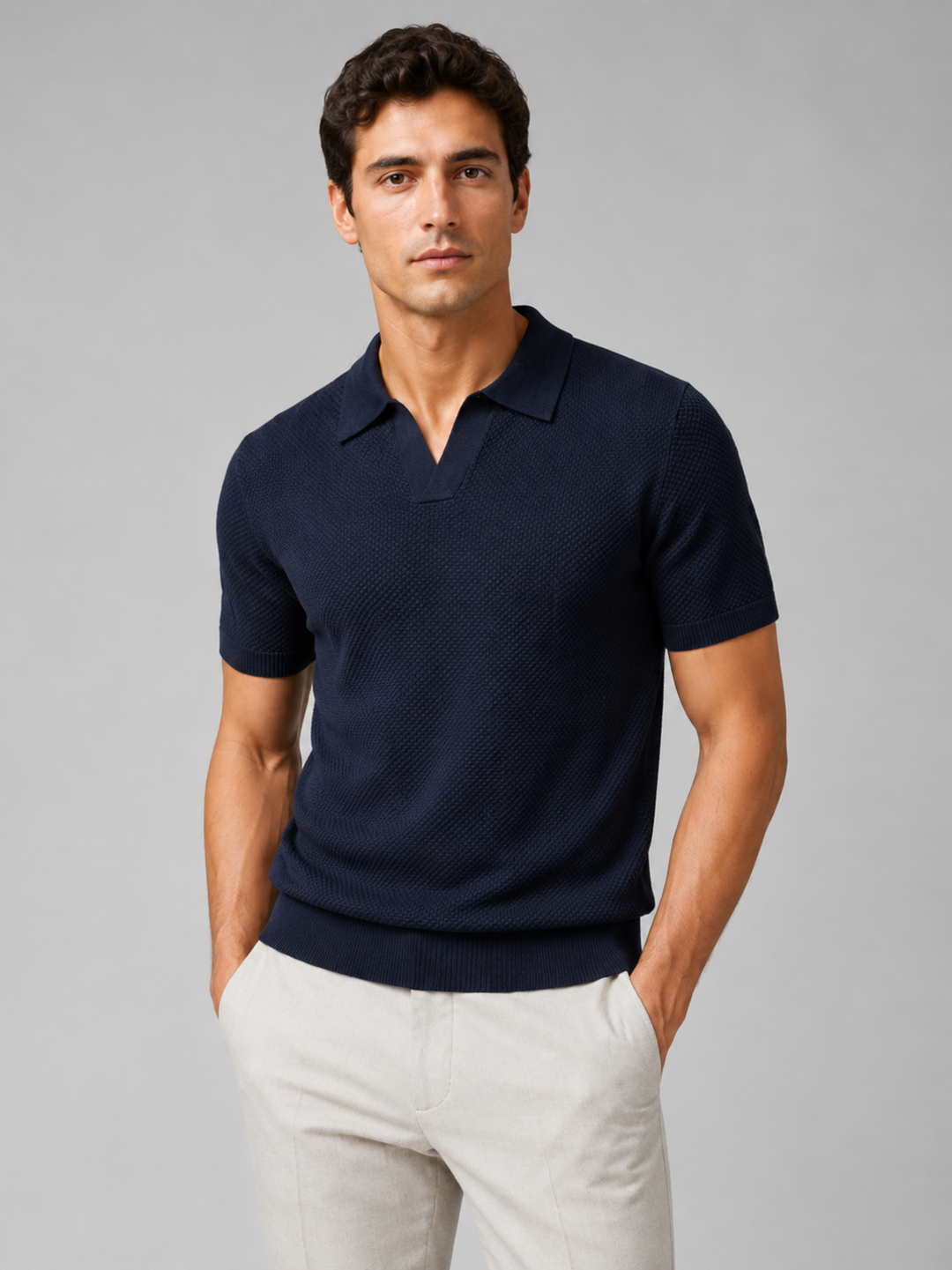 Homme portant le polo bleu marine en maille texturée avec pantalon clair, fond gris 35