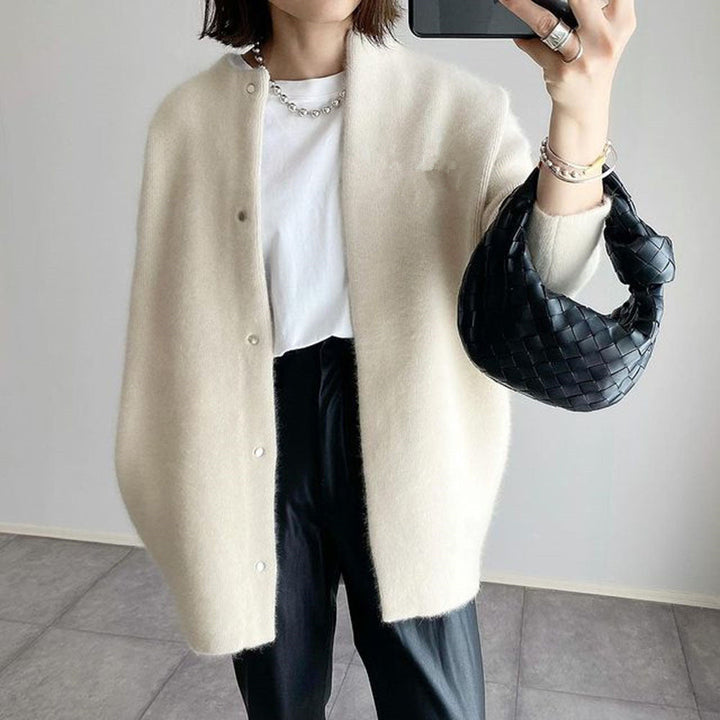 Gilet écru à col rond et boutons-pression, porté ouvert avec pantalon noir et petit sac tressé noir 2