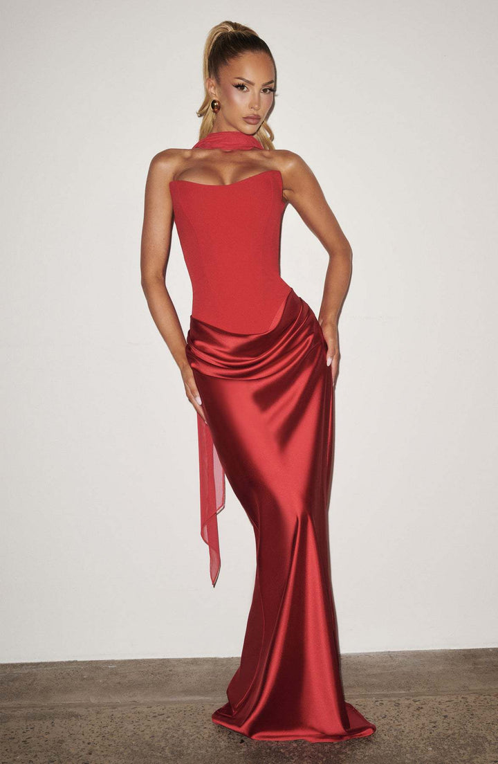 Mannequin en robe rouge avec voile drapé au cou, posant les mains sur les hanches devant un mur clair 31