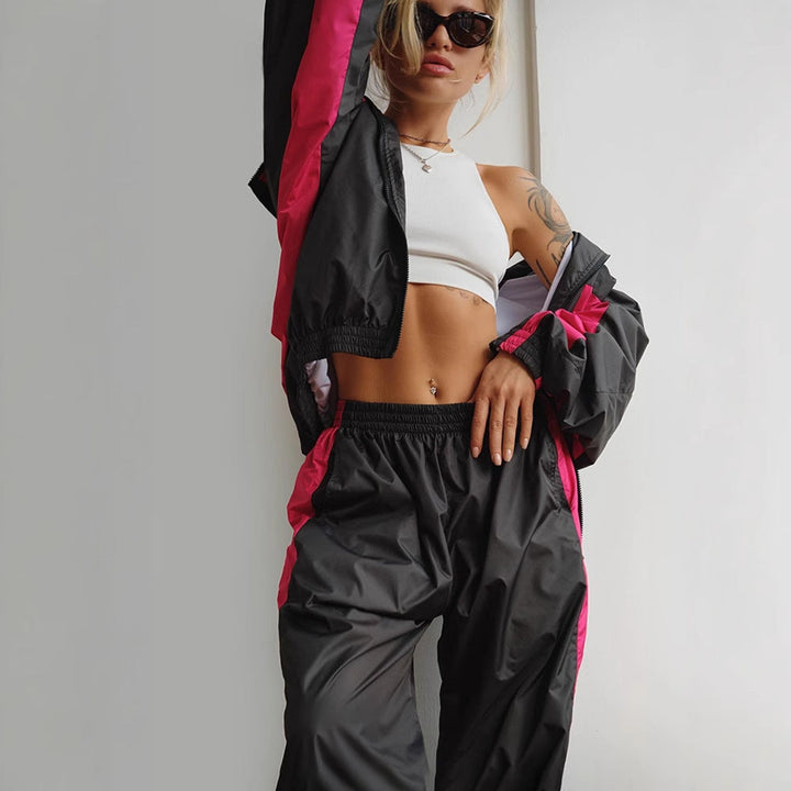 Plan rapproché d'un ensemble noir à bandes rose vif, veste ouverte sur un top blanc, pantalon à taille élastique. 10