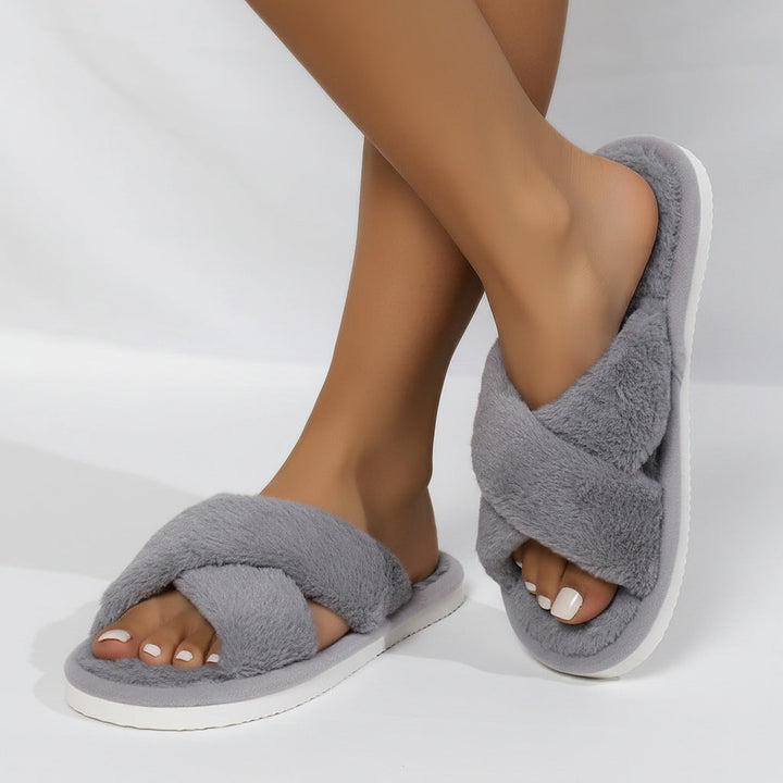 Chaussons gris à brides croisées en peluche portés, vus de côté, avec semelle blanche. 5