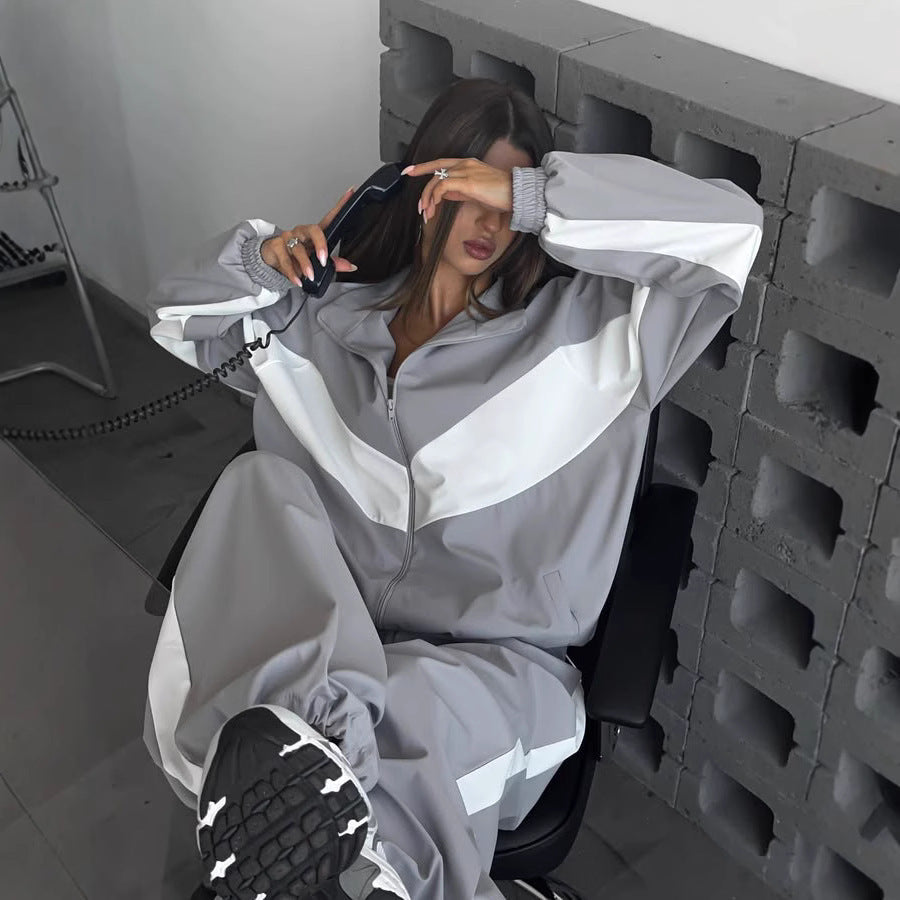 Modèle assise sur un fauteuil, un téléphone filaire à l'oreille, portant l'ensemble gris à larges bandes blanches en chevron. 1