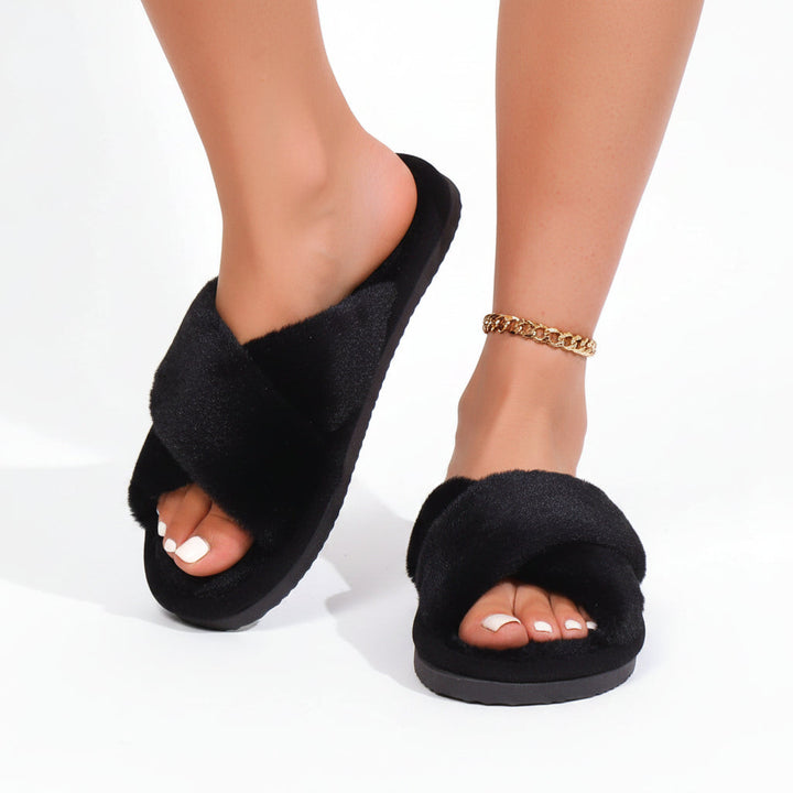 Chaussons noirs à brides croisées en peluche portés par une femme, avec une chaîne dorée à la cheville. 3