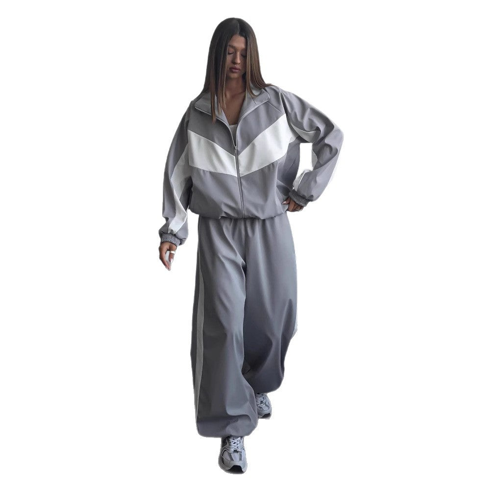 Modèle sur fond blanc marchant en ensemble gris à chevron blanc, veste zippée à col montant et pantalon ample resserré aux chevilles. 9