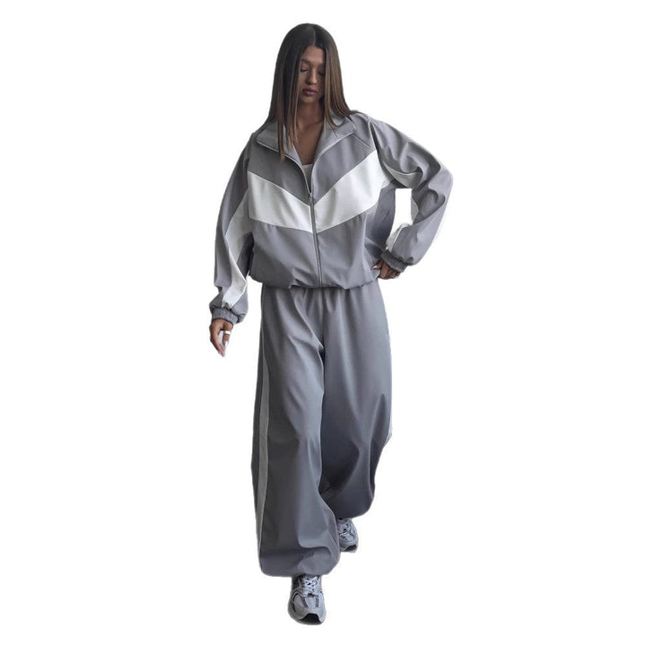 Modèle sur fond blanc marchant en ensemble gris à chevron blanc, veste zippée à col montant et pantalon ample resserré aux chevilles. 9