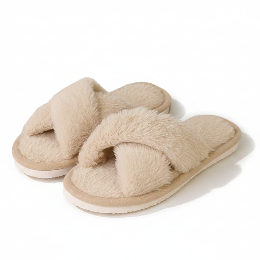 Paire de chaussons beiges en fausse fourrure à brides croisées, posée sur fond blanc, avec semelle blanche épaisse. 1