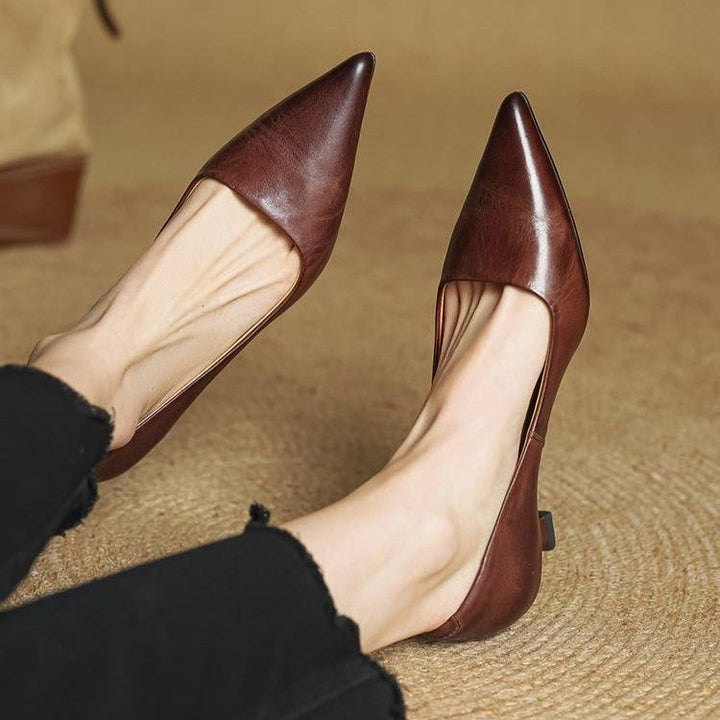 Pieds de femme portant les escarpins bruns à bout pointu, assise sur un tapis en fibres tressées 21
