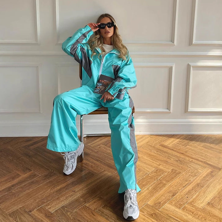 Modèle assise sur une chaise en lunettes de soleil, ensemble turquoise à bandes grises, veste zippée et pantalon large. 4