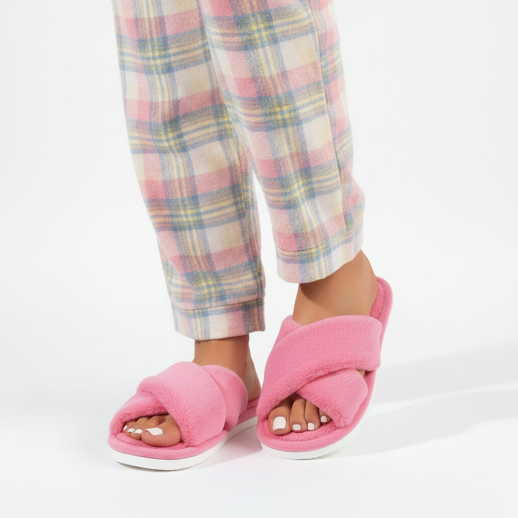 Chaussons roses à brides croisées en peluche portés avec un pantalon de pyjama à carreaux pastel. 2