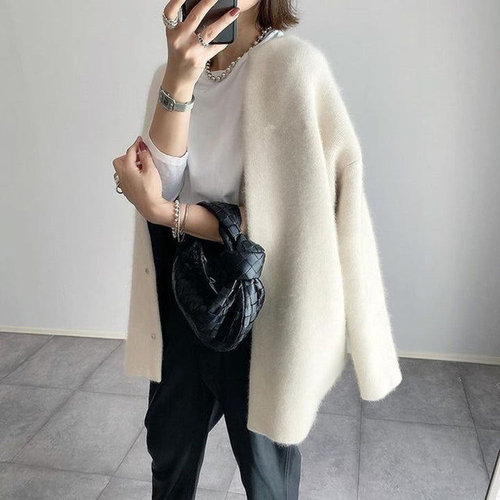 Gilet écru moelleux porté sur les épaules, vu de trois quarts, avec t-shirt blanc et pantalon noir 3