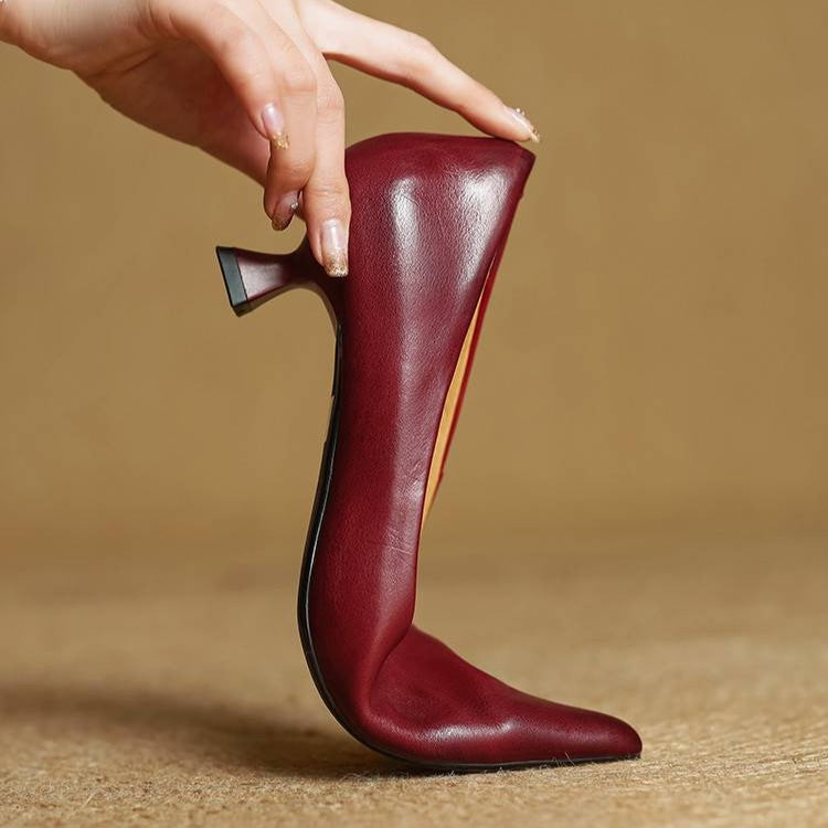 Escarpin rouge bordeaux tenu à la verticale par une main, montrant la semelle et le talon 10