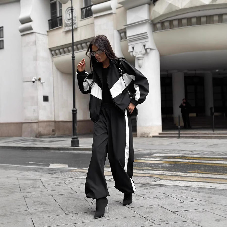 Ensemble noir à bandes blanches porté en marchant dans la rue, veste zippée et pantalon large resserré aux chevilles. 5