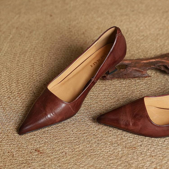 Paire d'escarpins bruns en cuir posée sur un tapis tressé, intérieur clair visible, à côté d'un morceau de bois 22