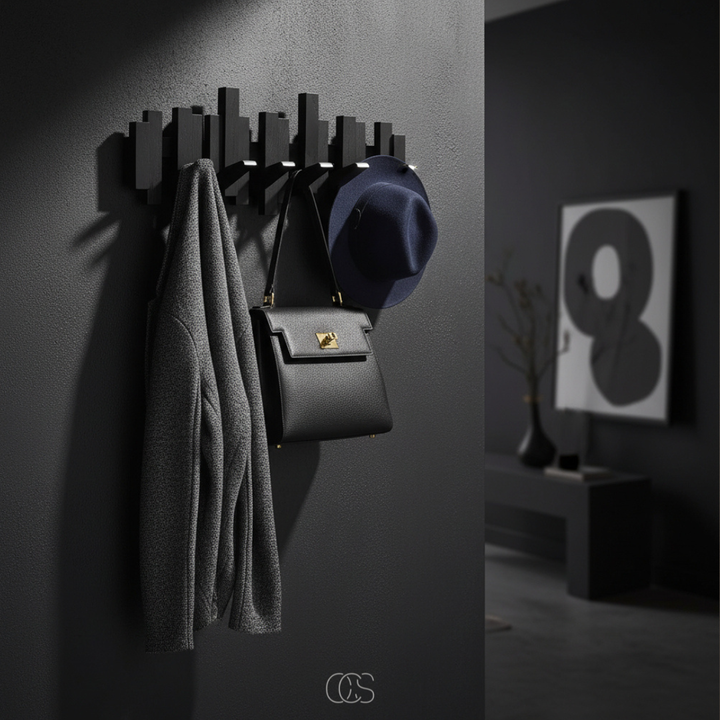 Porte-manteau mural noir aux lamelles décalées dans une entrée sombre, avec veste grise, sac à main noir et chapeau bleu marine suspendus. 2