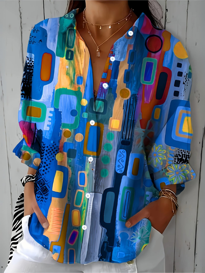 Blouse à motif abstrait bleu, orange et turquoise, vue de près sur un mannequin, manches retroussées et boutons blancs. 6