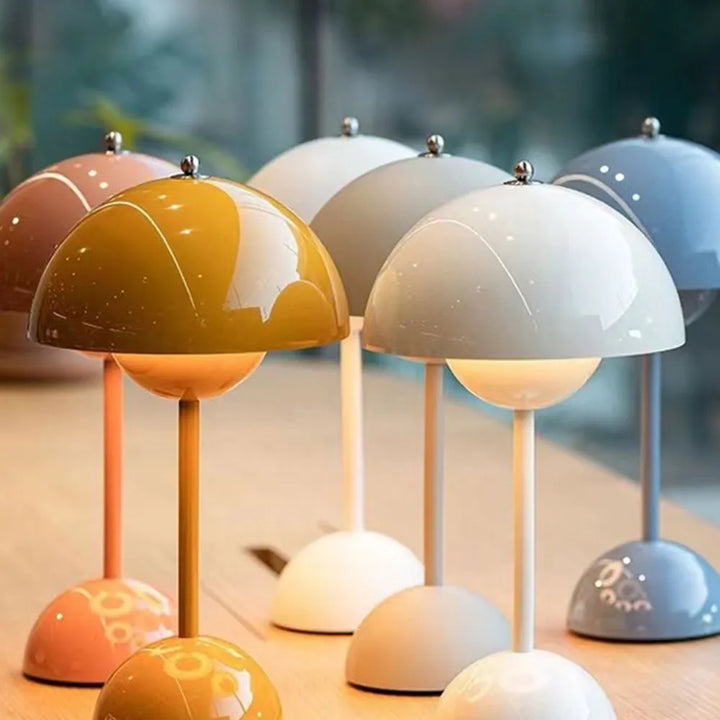 Gros plan de lampes champignon brillantes de plusieurs couleurs alignées sur une table en bois, avec reflets sur les dômes. 3